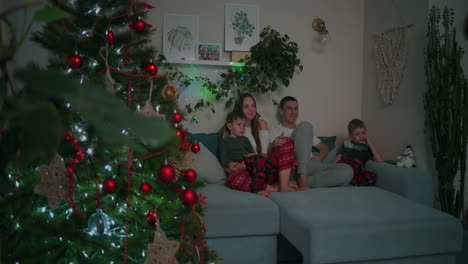 Family-Bonding-at-Christmas.-together-on-a-sofa-and-watching-TV-at-home-during-Christmas-holidays.-High-quality-4k-footage